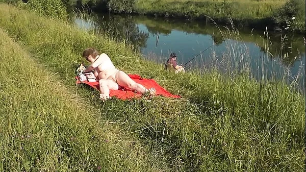 MILF sexy Frina on river bank undressed and sunbathes naked. Random man fisherman watching for her, and in the end decided to join naked woman. Wild beach. Nudist beach. Public nudity. Public exposure. Naked in public